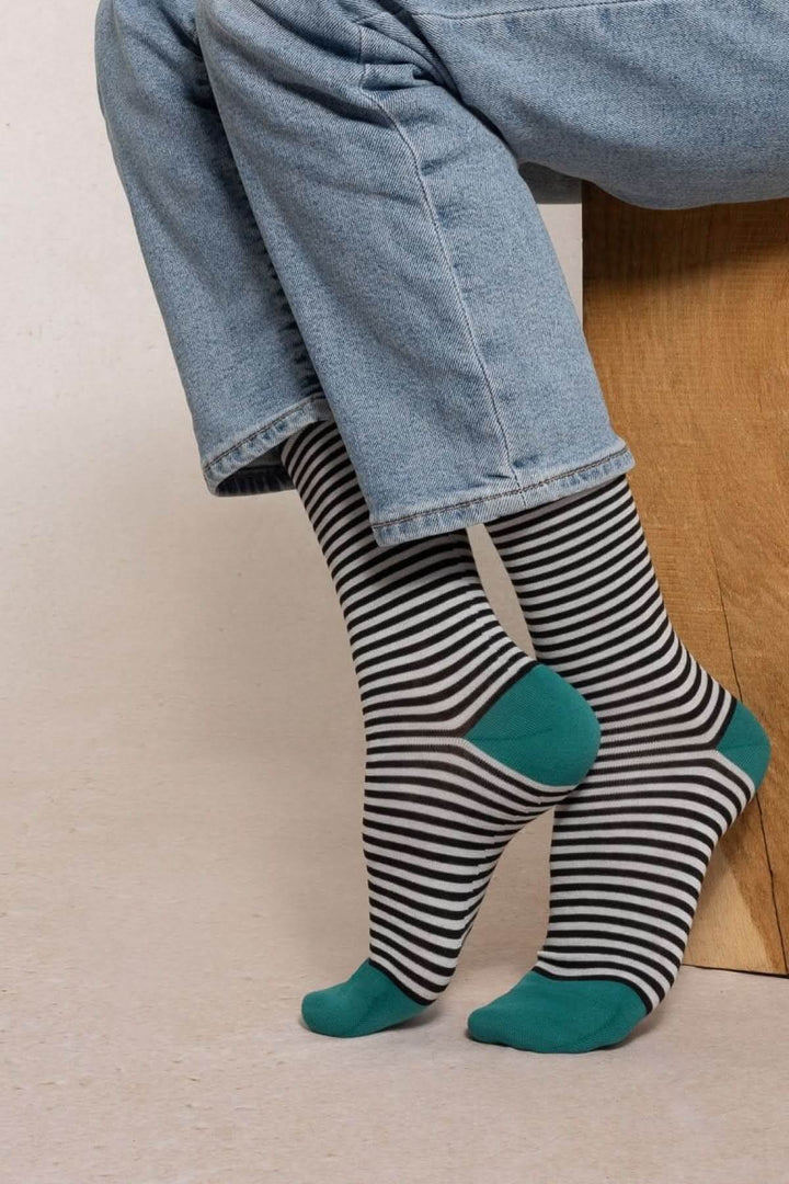 Person wearing Chaussettes à rayures fines with green accents and stylish jeans