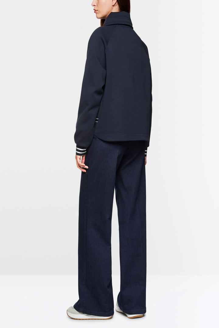 Femme portant un sweat-shirt zippé ample avec cordon de serrage, vu de dos, associé à un pantalon décontracté.