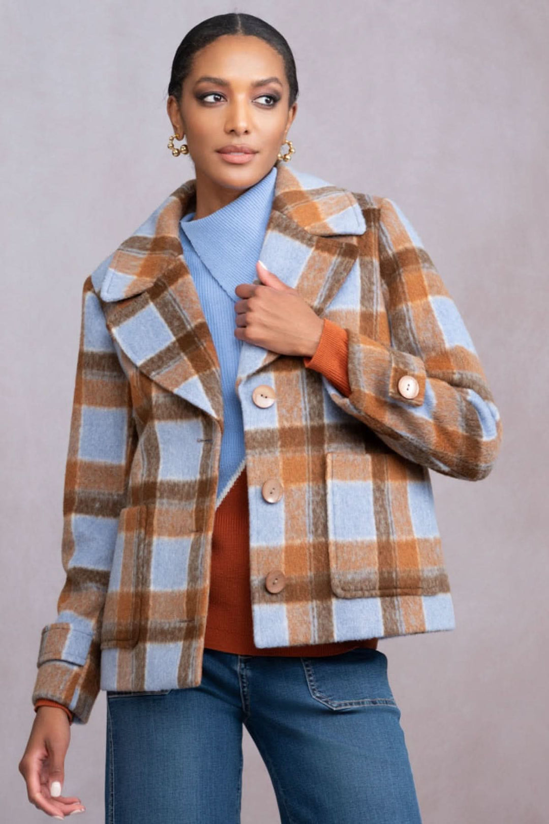 Veste courte à carreaux aux tons orange et bleu, associée à un pull en laine pour un look automnal élégant.