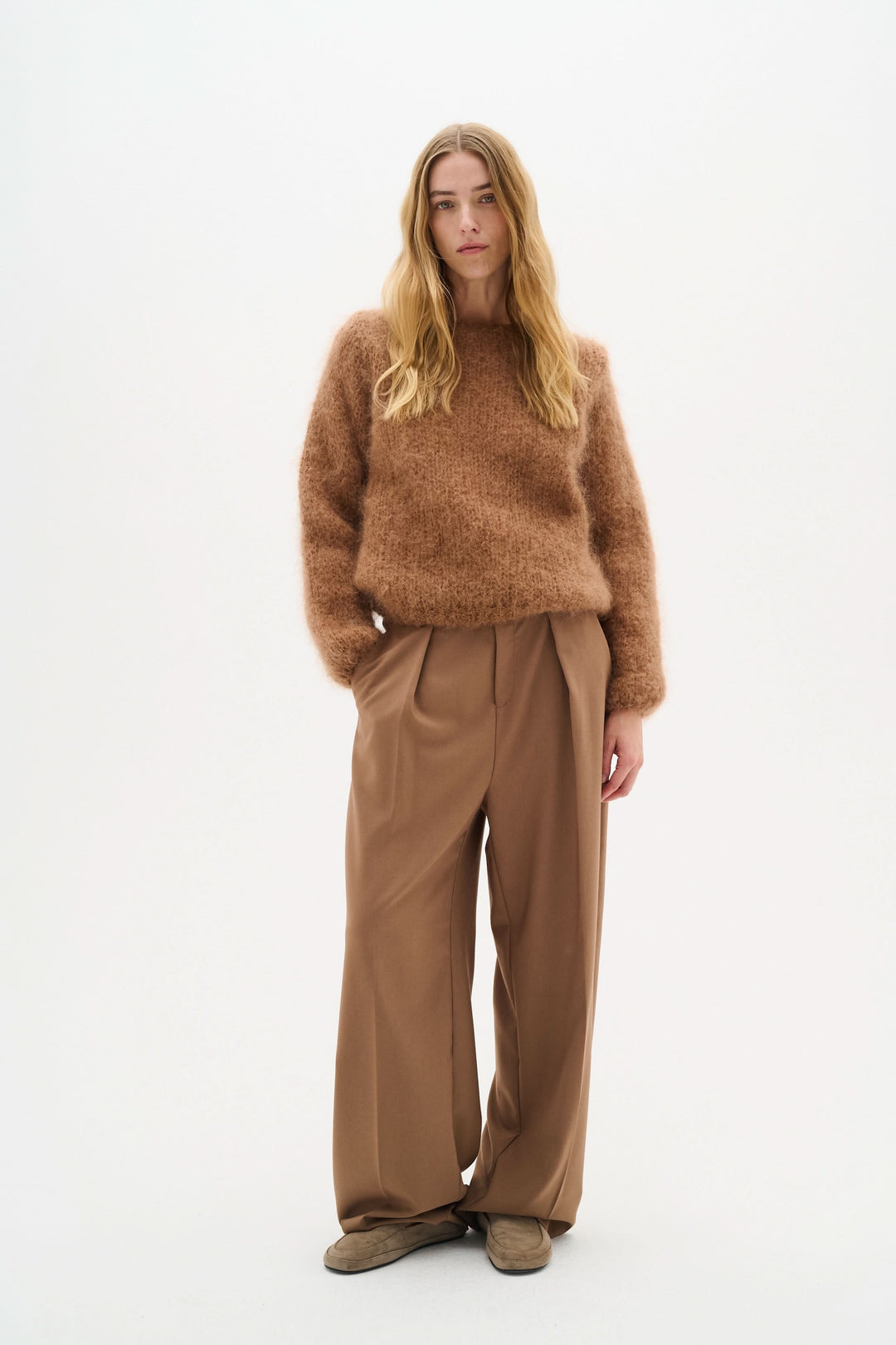 Femme en chandail en maille duveteuse marron et pantalon ample, style cosy et élégant.