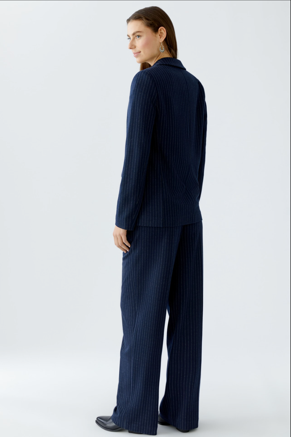 Femme portant un veston fines rayures, vue de dos, style décontracté avec pantalon assorti.