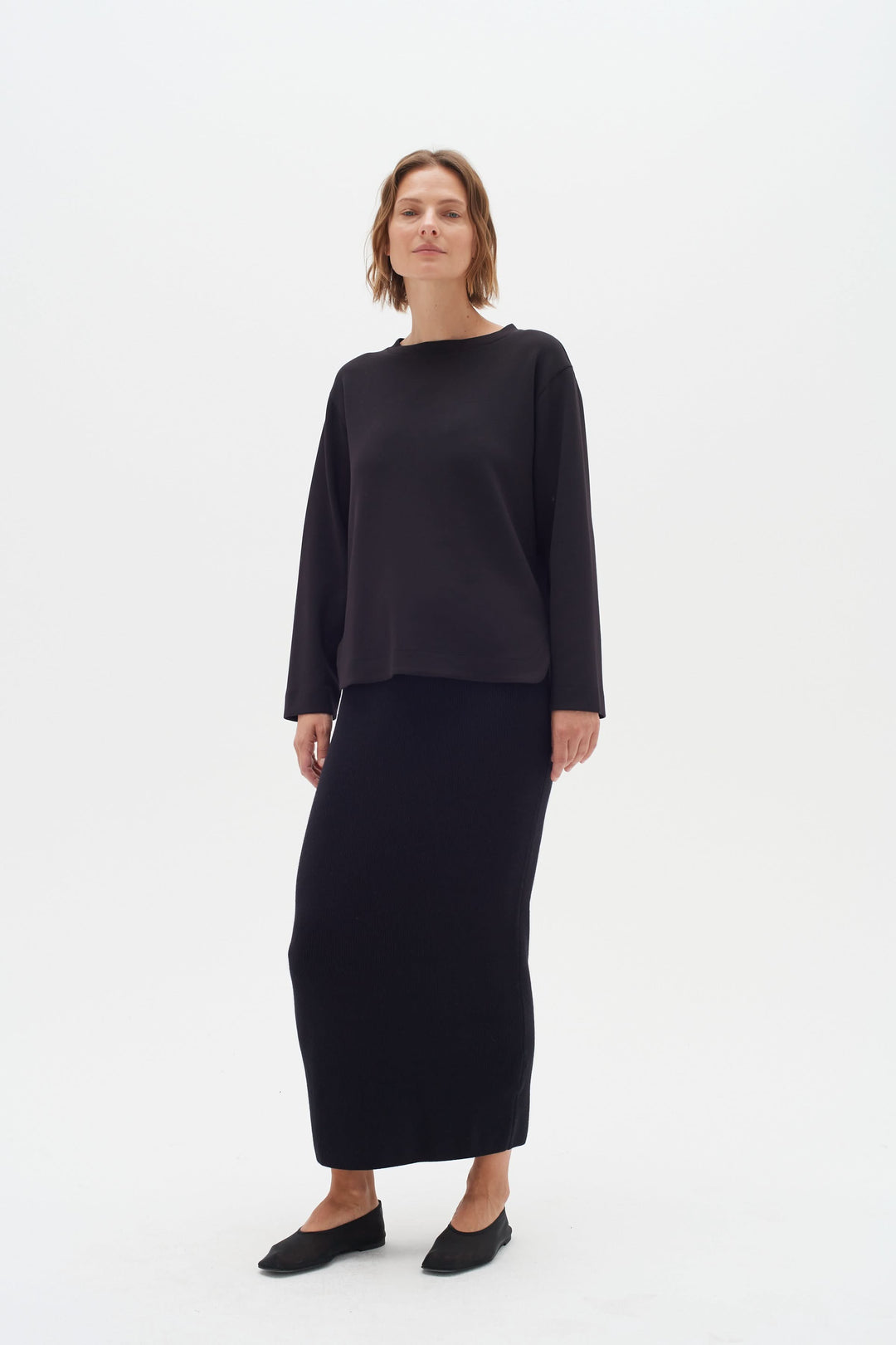 Chandail Gincent noir à manches longues avec jupe assortie, style élégant et minimaliste, col bateau.