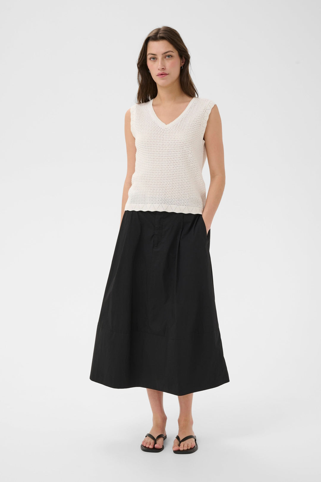 Haut en maille ajourée Bolissa sans manches avec encolure en V, porté par une femme, offre une silhouette légère et décontractée. Décris moi le produit en français.