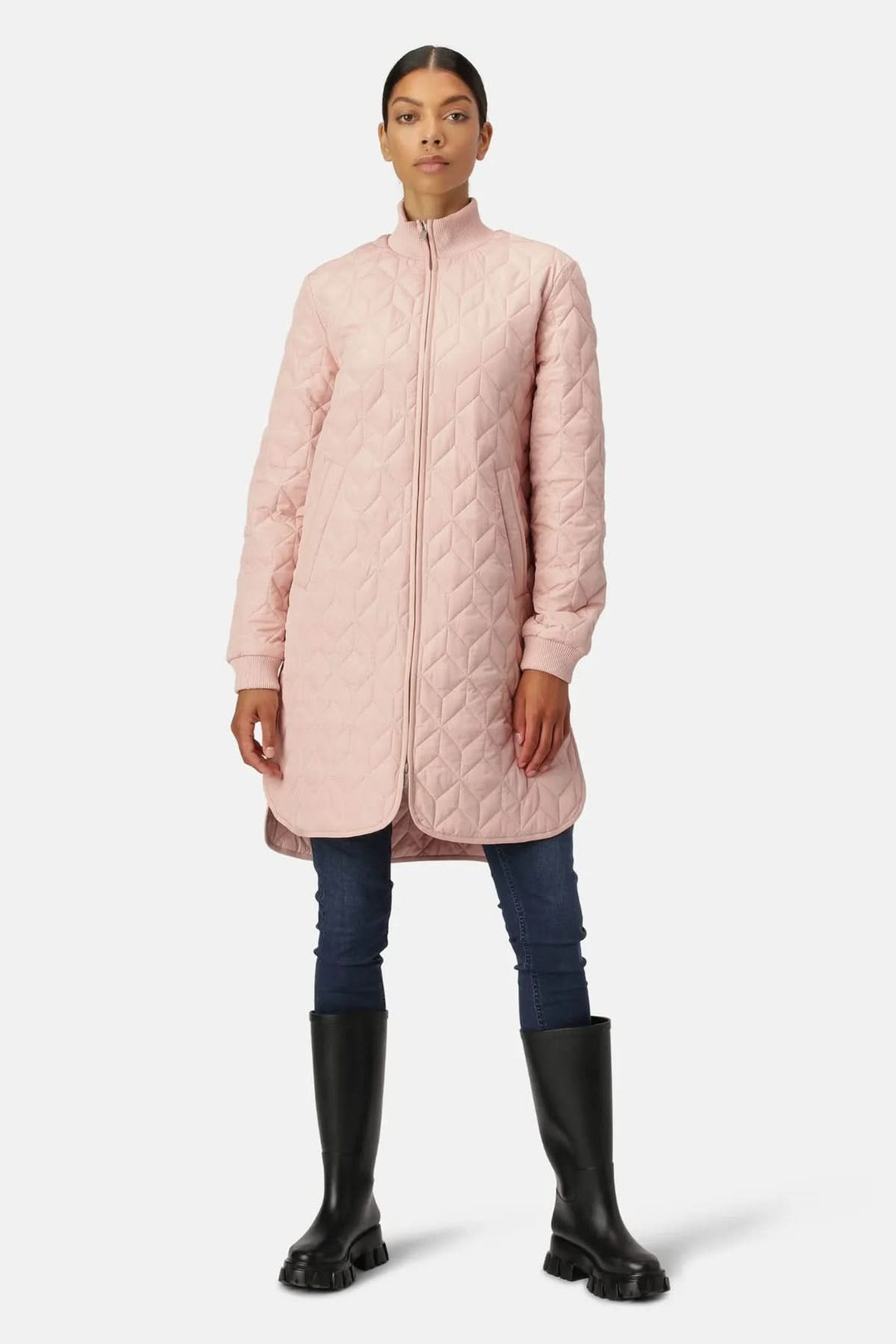 Manteau matelassé long à col montant rose avec motifs géométriques, porté avec jean ajusté et bottes hautes, style urbain élégant.