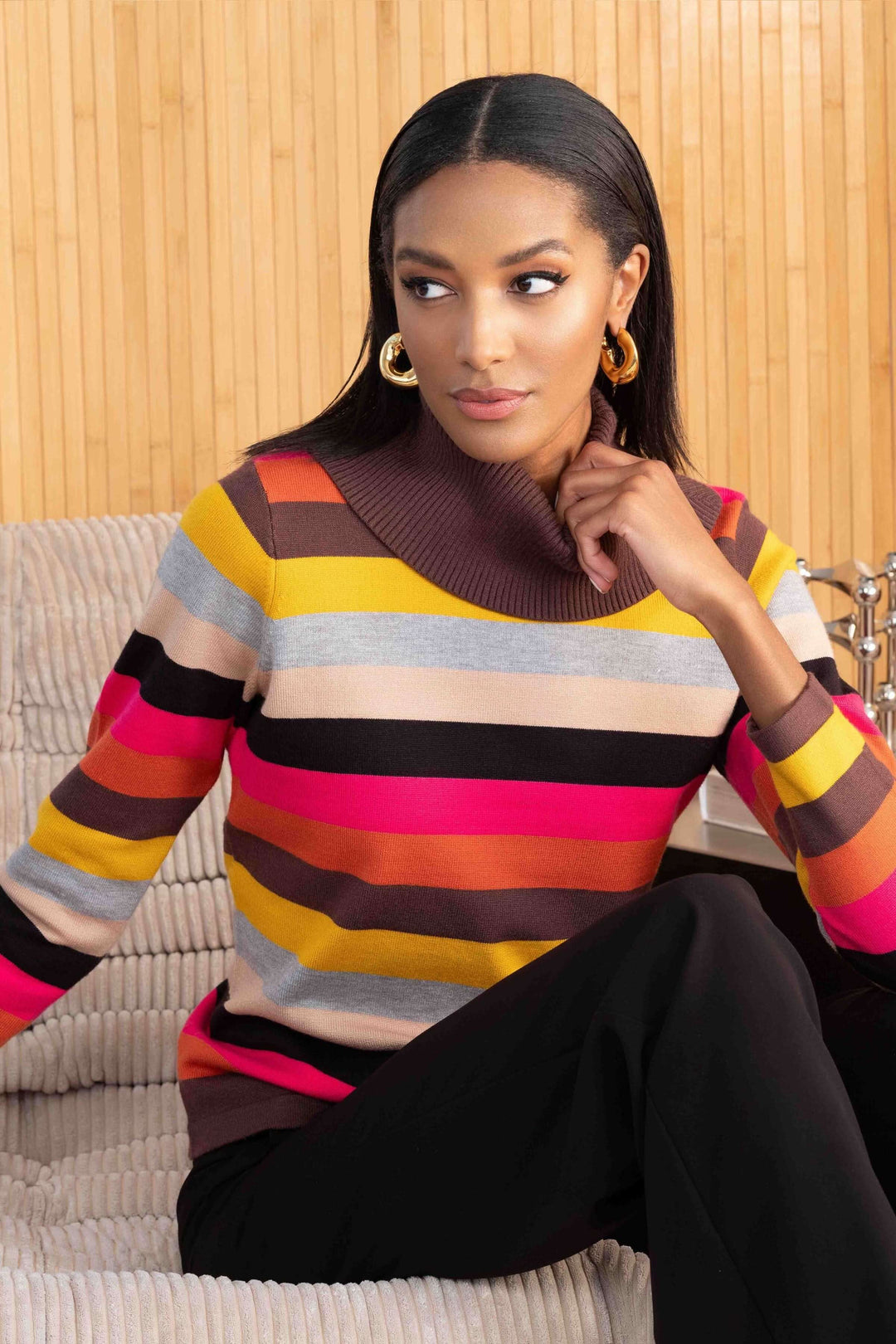 Pull tricot rayé multicolore à col roulé, style contemporain et confortable, porté avec un pantalon noir.