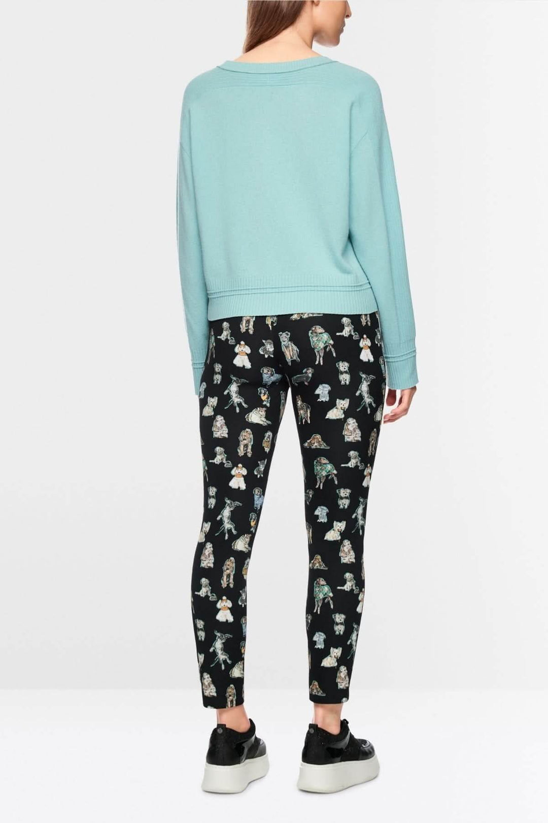 Vue arrière d'un chandail manches longues bleu avec design minimaliste et coupe ample, porté avec un legging imprimé.