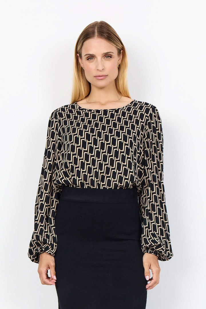 Blouse à motif graphique géométrique avec encolure ronde et manches bouffantes, portée avec une jupe crayon.