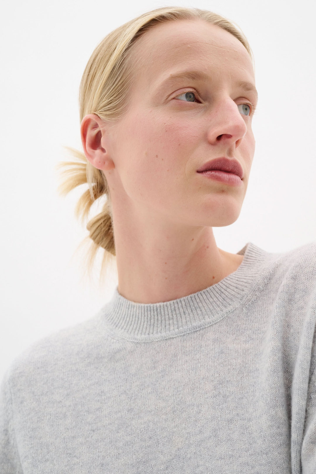 Modèle portant un chandail Silje en maille fine, couleur gris clair, avec encolure ronde et coupe droite.