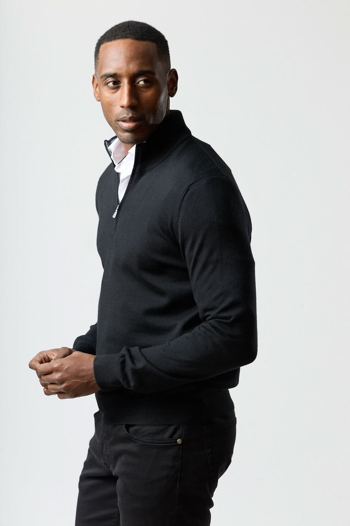 Homme portant un chandail à demi-zip en laine mérinos, élégant et moderne, couleur noire, avec col demi-glissière, style décontracté.