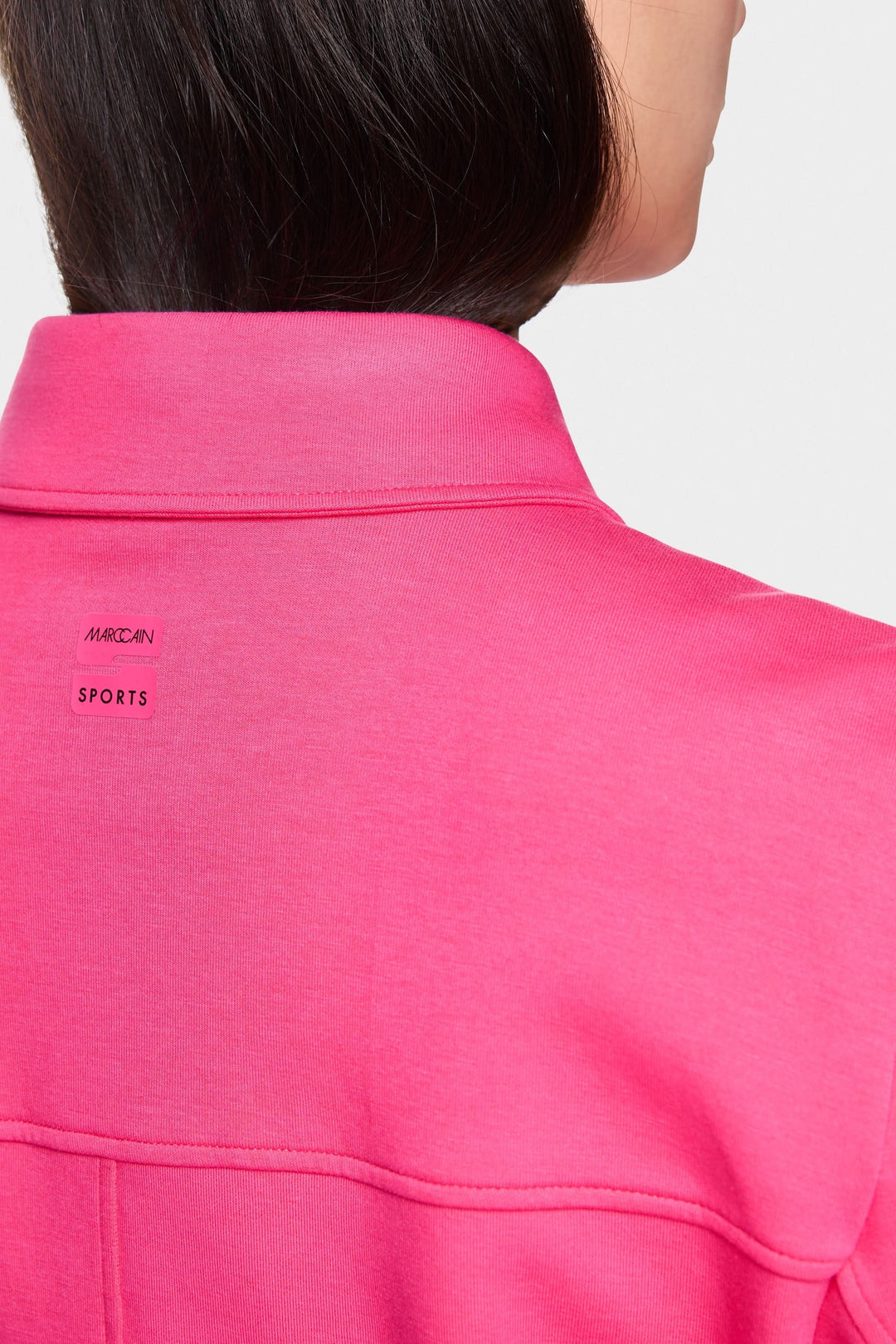 Détail du col d'une veste moderne rose, mettant en avant la marque et le style décontracté.