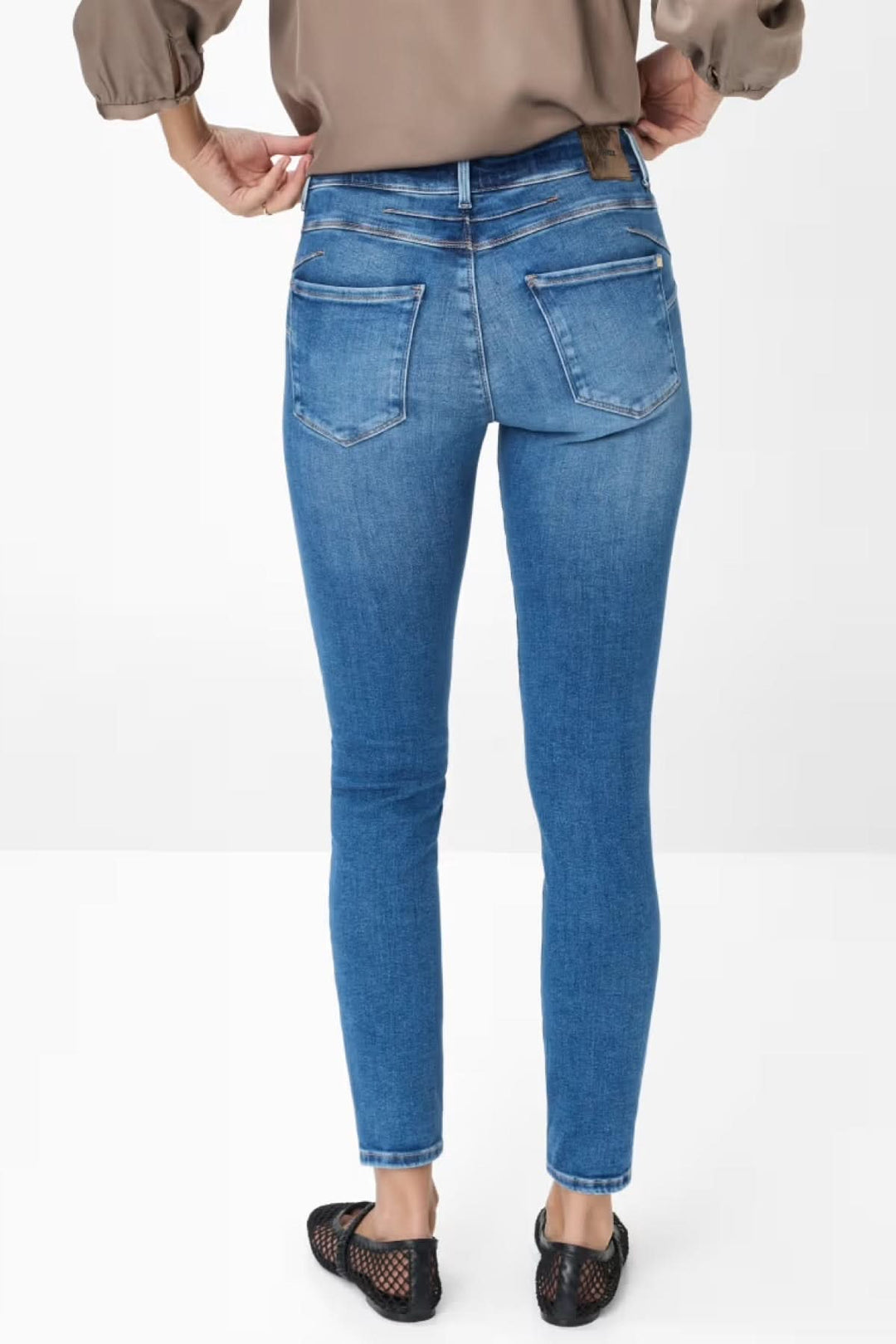 Jean skinny Ana en denim bleu clair avec taille mi-haute, vue arrière, porté avec blouse fluide et ballerines.