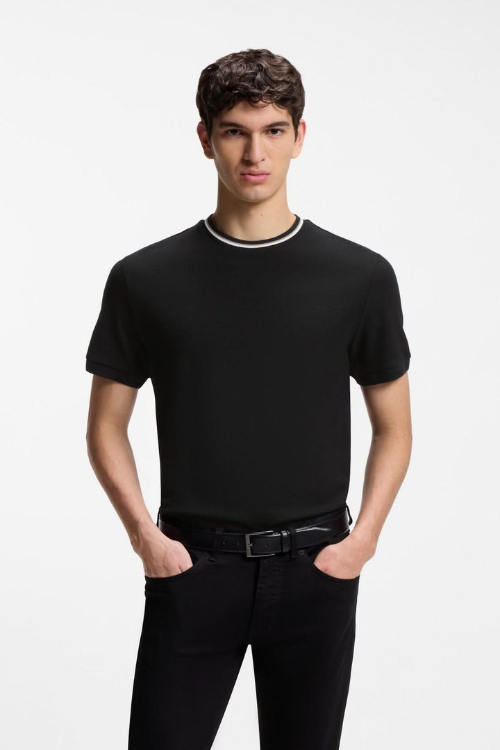 Homme portant un T-shirt à encolure contrastée noir avec bordure blanche, idéal pour un look moderne et décontracté.