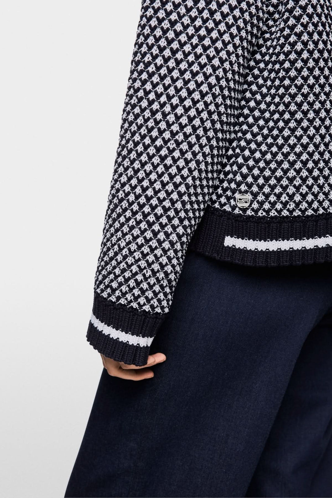 Chandail court tricoté en noir et blanc avec motif texturé, porté sur un pantalon fluide.