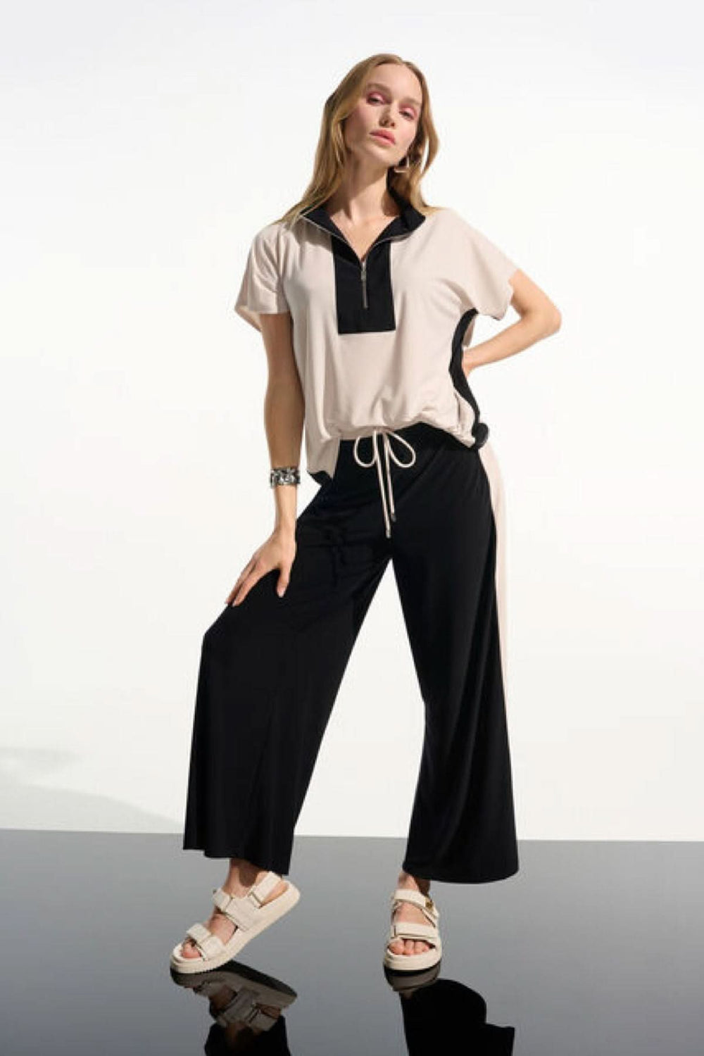 Femme portant un Haut à col zippé structuré avec pantalon noir, style moderne et épuré.