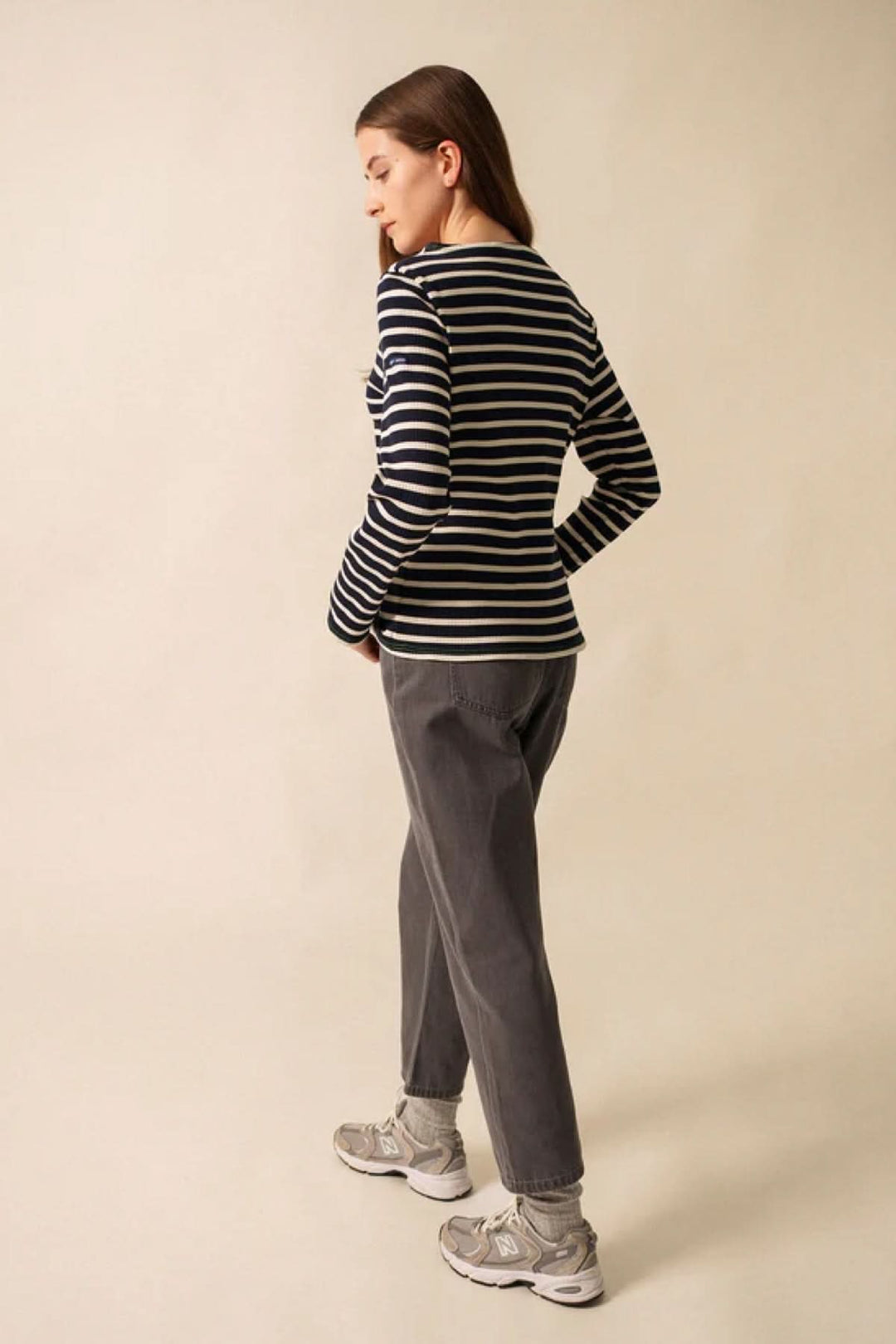 Femme portant un chandail à manches longues à rayures noires et blanches, style décontracté avec coupe ajustée, en extérieur.