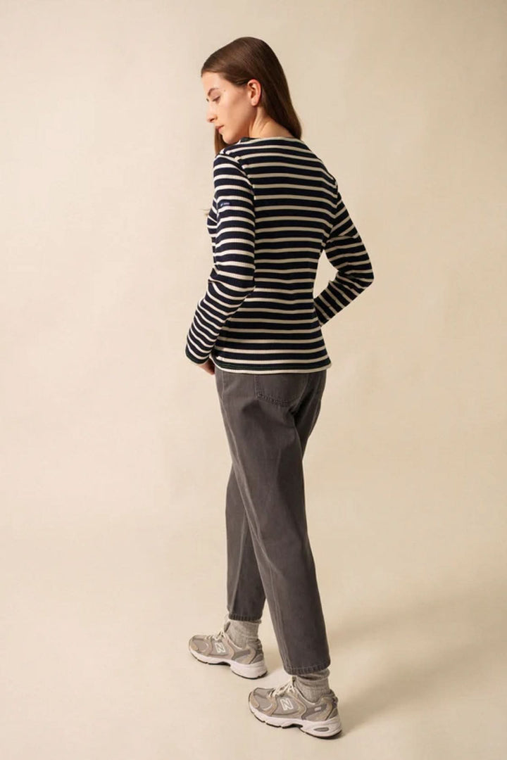 Femme portant un chandail à manches longues à rayures noires et blanches, style décontracté avec coupe ajustée, en extérieur.
