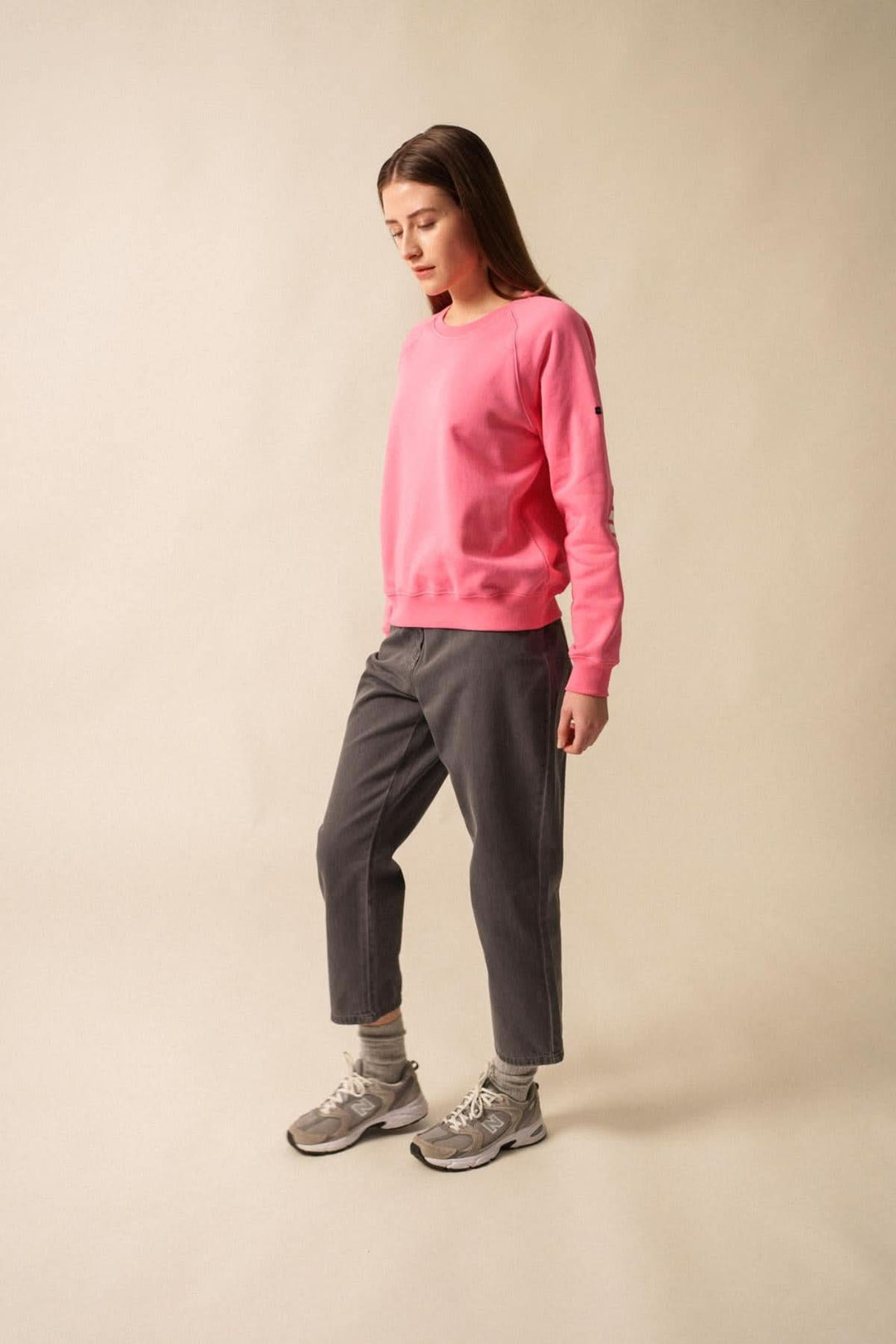 Femme en sweat rose confortable, pantalon gris, look décontracté, mode casual.