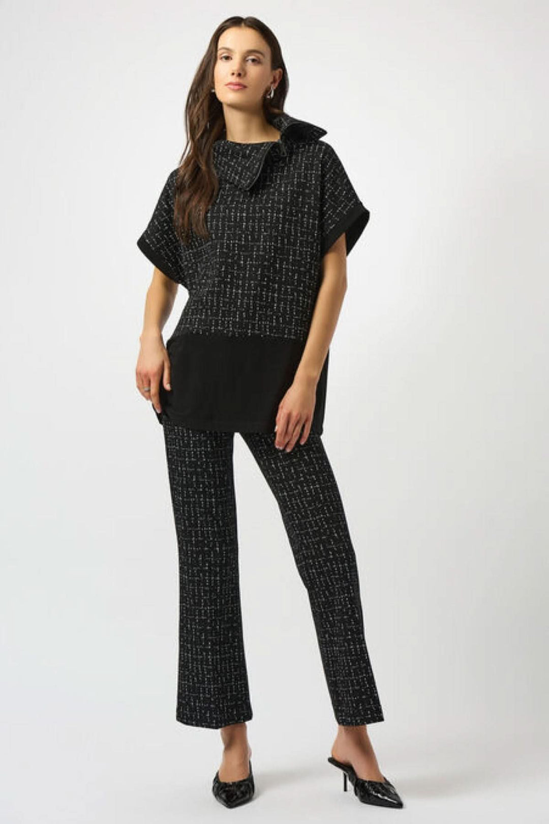 Haut col montant noir à motifs graphiques blancs, pantalon noir assorti, style moderne et structuré.