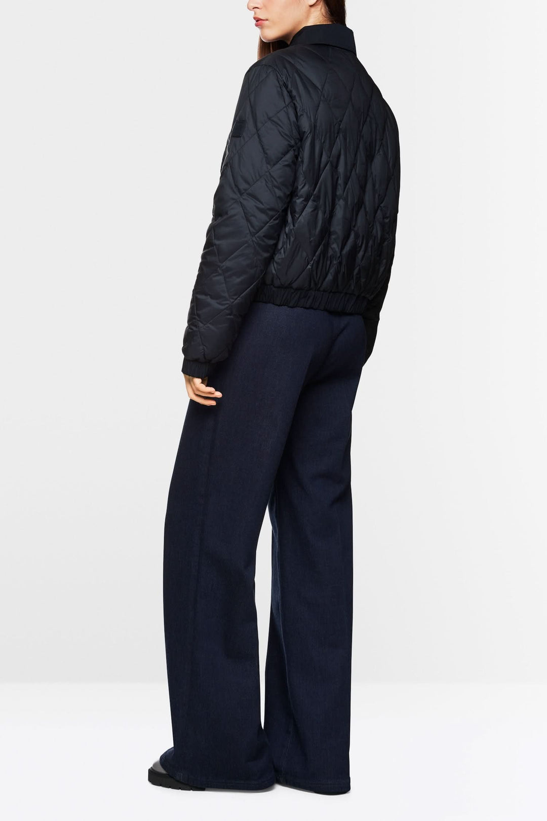 Veste matelassée noire « Rethink Together » vue de dos, stylée avec un pantalon ample en laine.