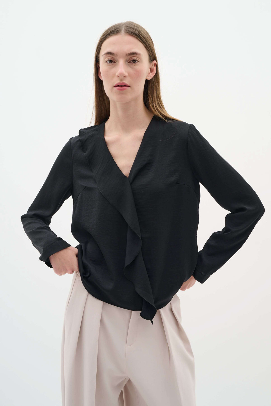Blouse Auda noire à col en V et volant, élégante et fluide, parfaite pour un look chic.