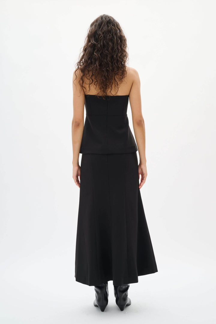 Femme en Camisole Zoeh bustier structurée noire, sans bretelles, coupe ajustée, de dos, tenue élégante et minimaliste parfaite pour occasions habillées.