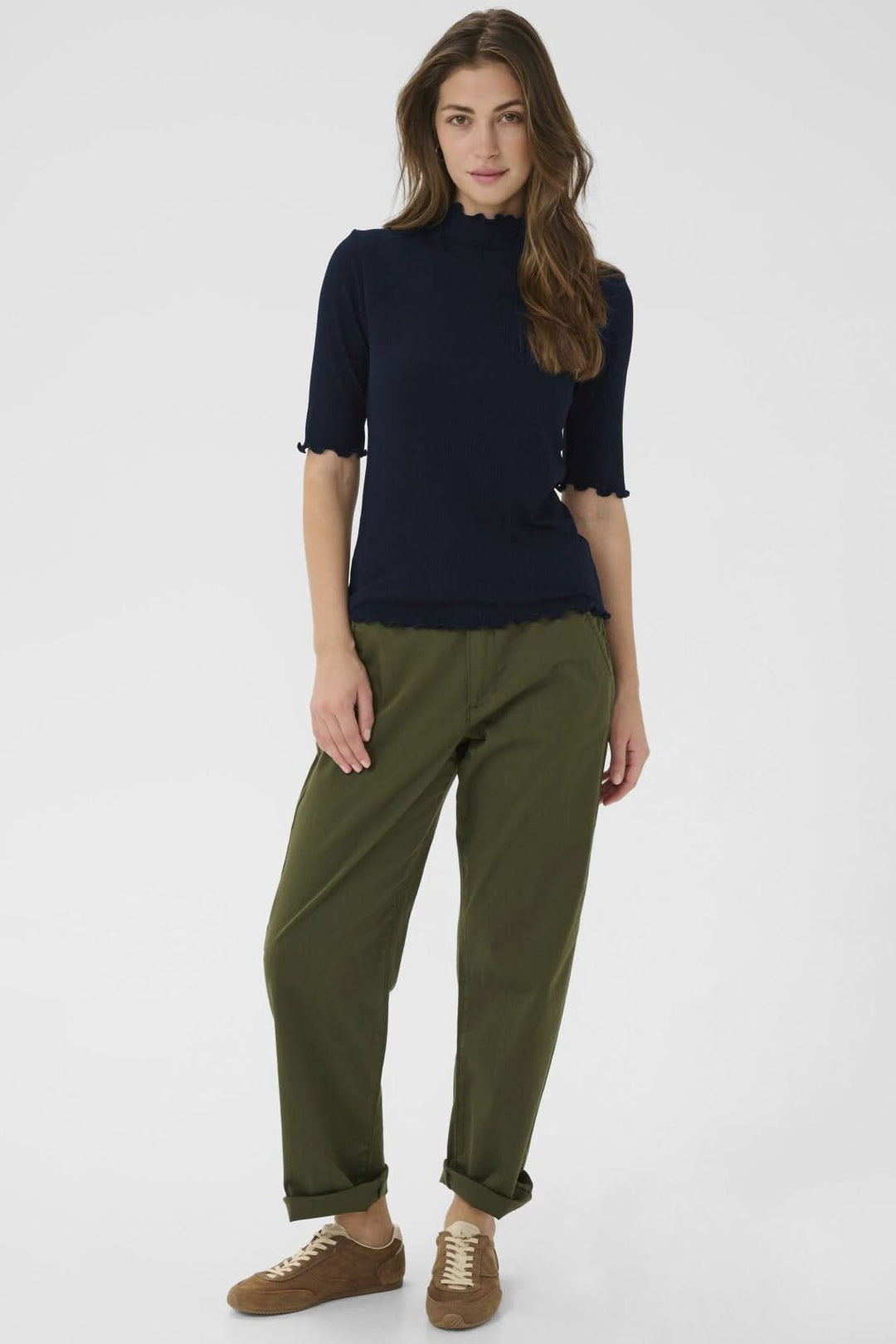 Femme portant le T-shirt Ribba à col montant avec maille côtelée bleu, manches mi-longues, et finitions festonnées élégantes.