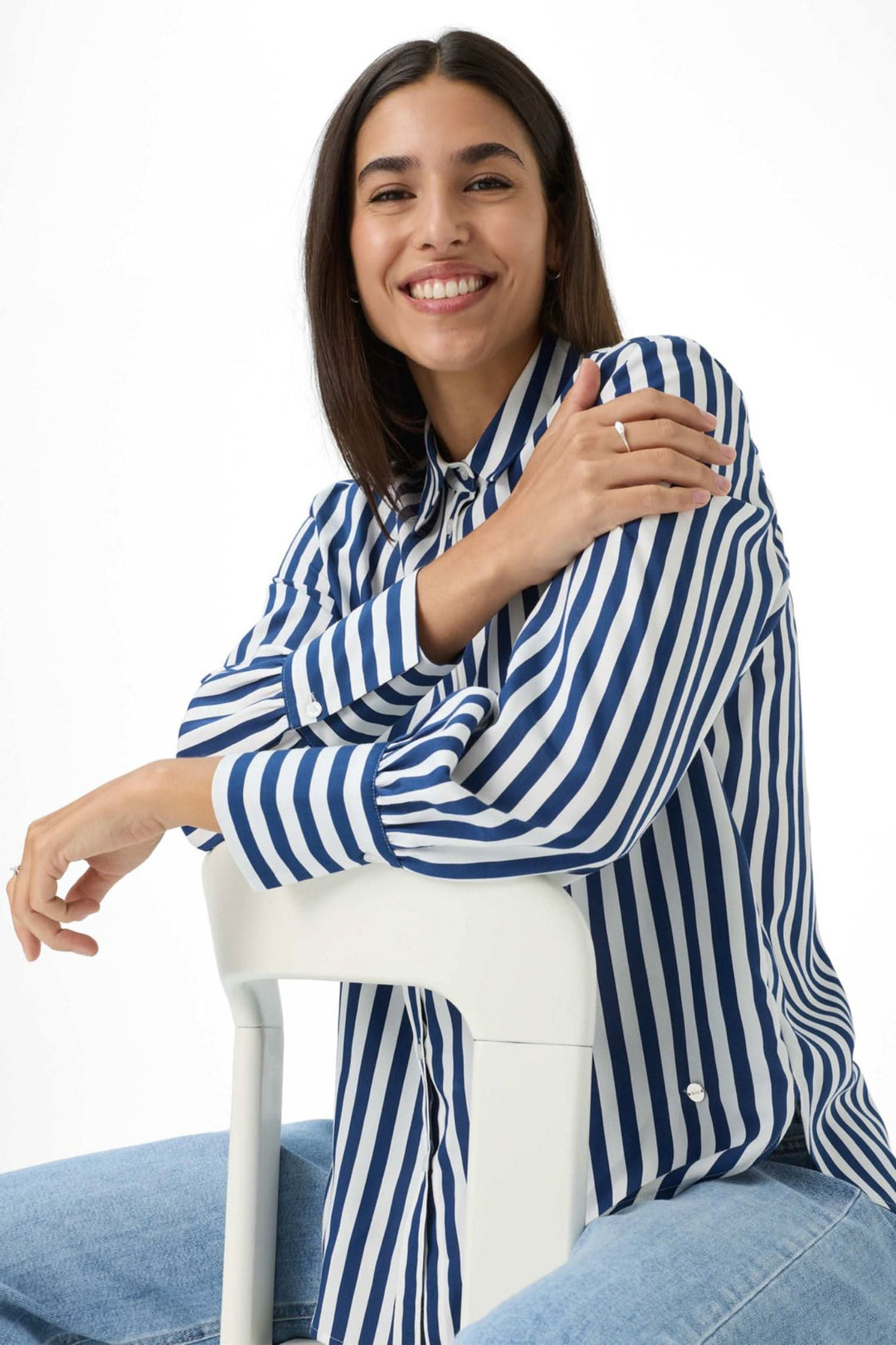 Chemise Vic rayée bleue et blanche, coupe évasée, portée avec sourire par un modèle assis sur une chaise.