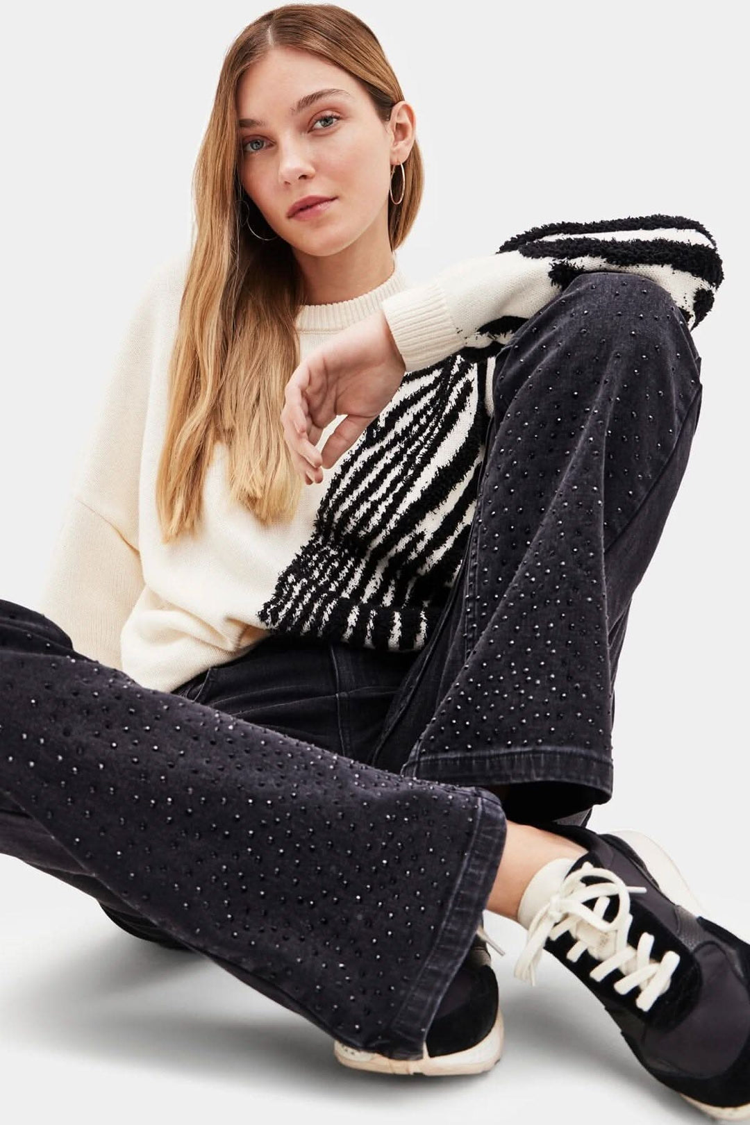 Pantalon taille haute large en denim noir avec pierres brillantes, femme assise, au style décontracté.