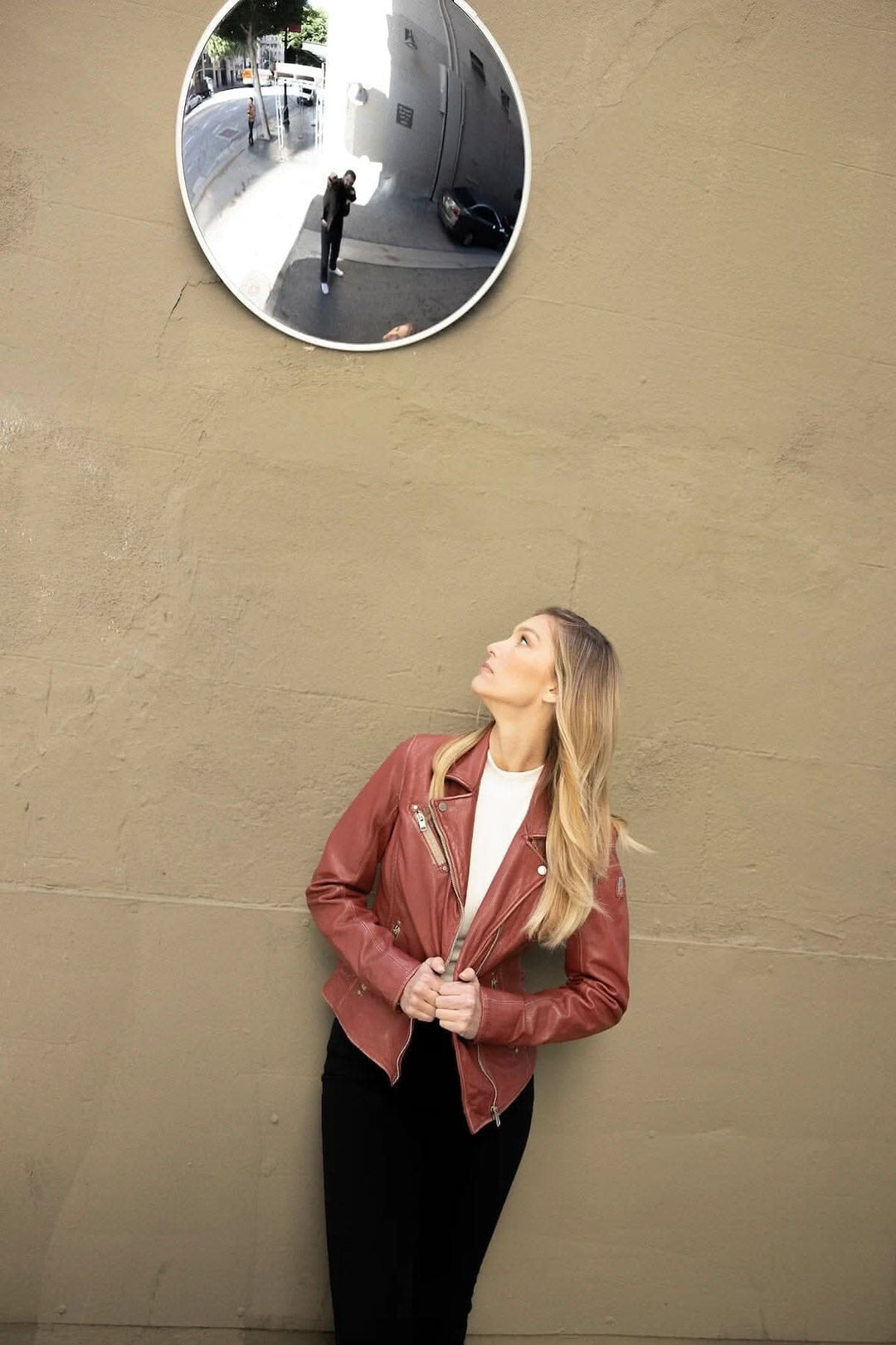 Femme admirant son reflet dans un miroir tout en portant une veste en cuir Sofia marron.