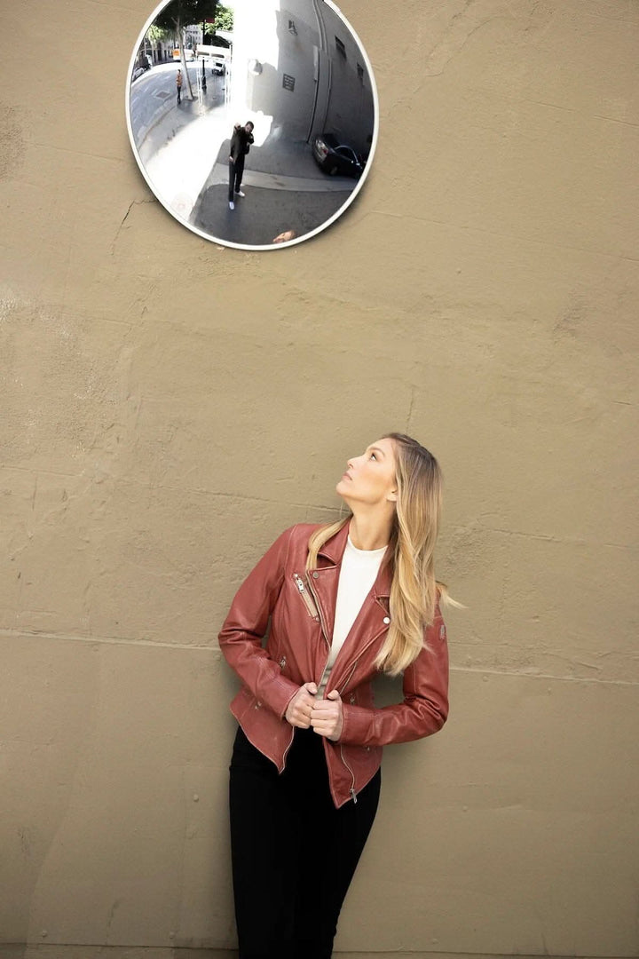 Femme admirant son reflet dans un miroir tout en portant une veste en cuir Sofia marron.