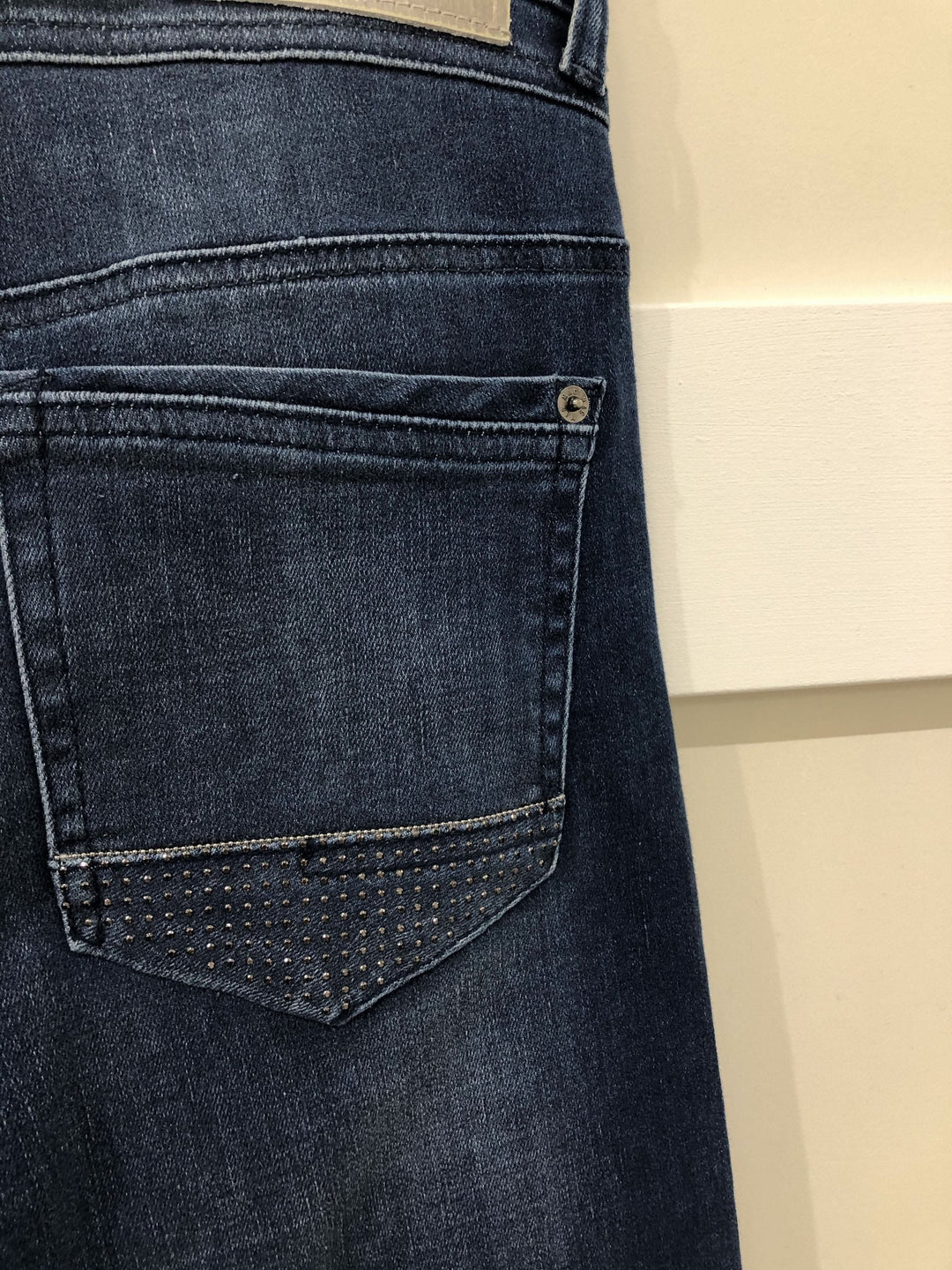 Détails d'un jean bleu délavé avec des brillants sur la poche arrière, modèle Jean Rich.